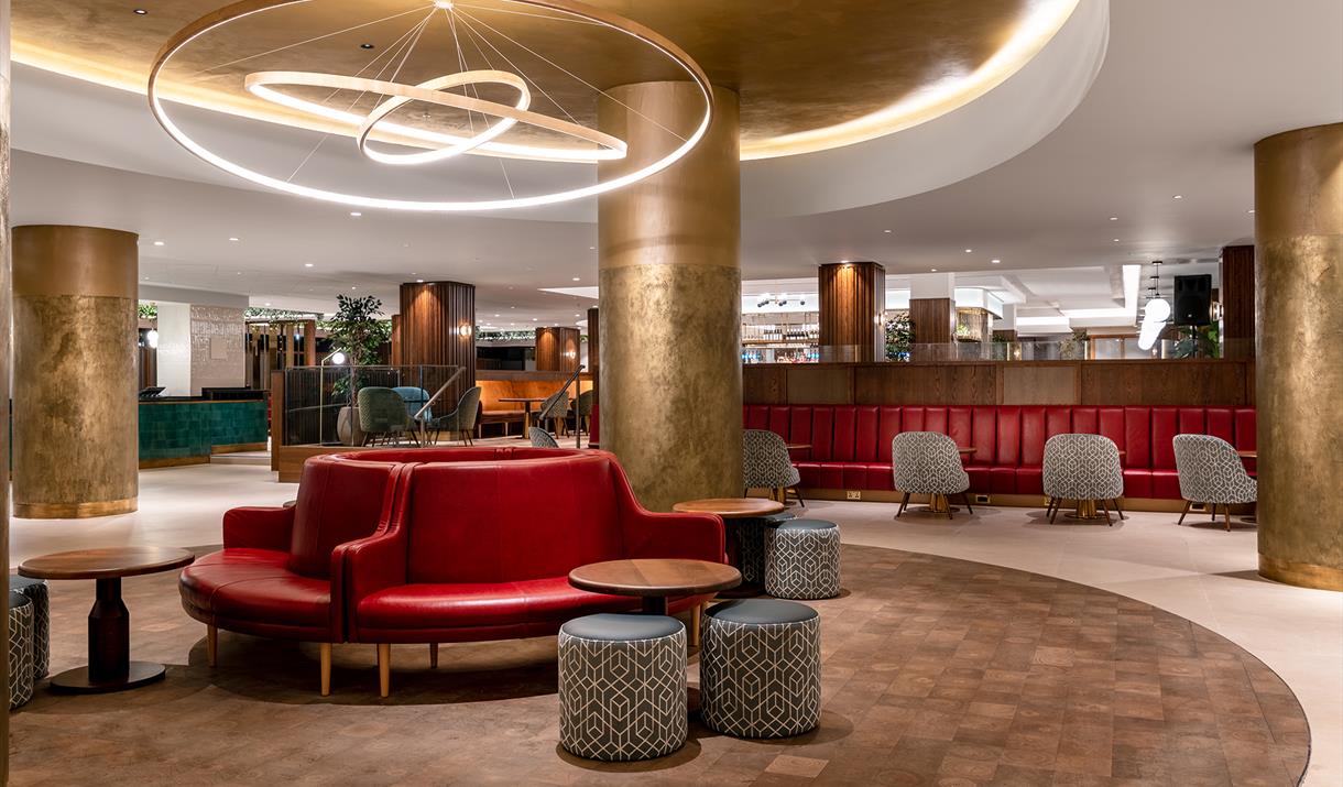 Lobby shot with red sofas in Centre and chairs and bar in background