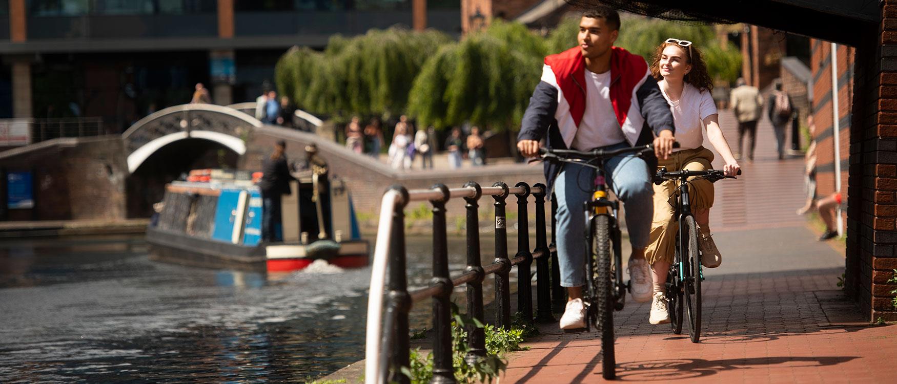 A couple riding a bike along Birmingham's canalside