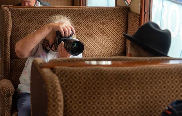 Photography of Woman taking photograph of 1940s Re-enactor on vintage train carriage