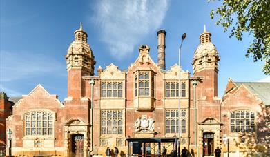 a photo of the facade of Moseley Road Baths, taken from the opposite side of the road, its sunny with blue skies behind the building 
