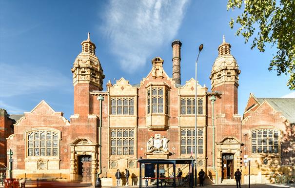a photo of the facade of Moseley Road Baths, taken from the opposite side of the road, its sunny with blue skies behind the building