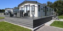 Caravan with grey decking and glass fence