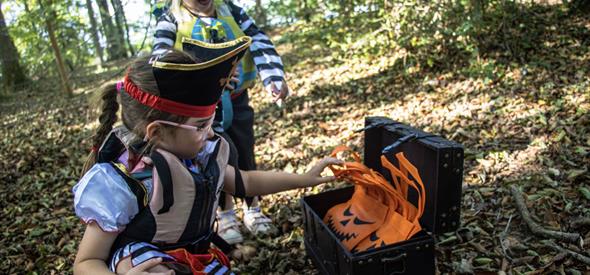 Two young children in pirate fancy dress opening a treasure chest 