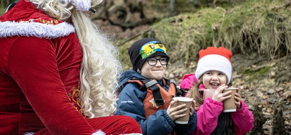 Father Christmas drinking hot chocolate with two children in a kayak 