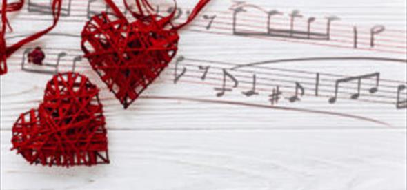 Musical notes painted onto the wooden background and two red wicker hearts are sat on top.