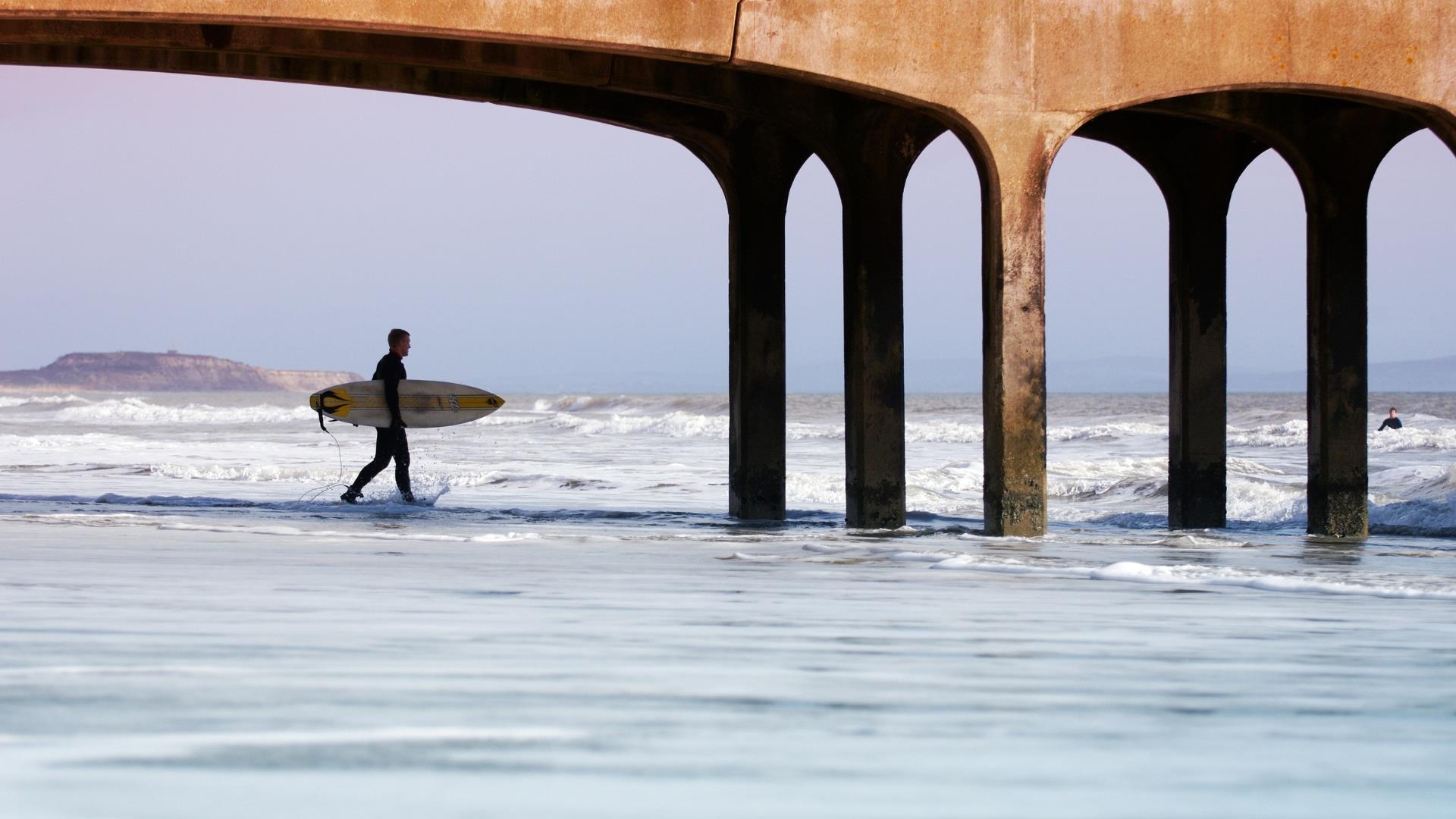 Surfing walking along beach towards the ocean