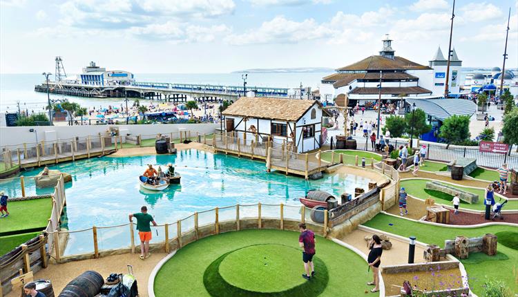 Visitors enjoying an 18 hole adventure golf course overlooking Bournemouth Pier