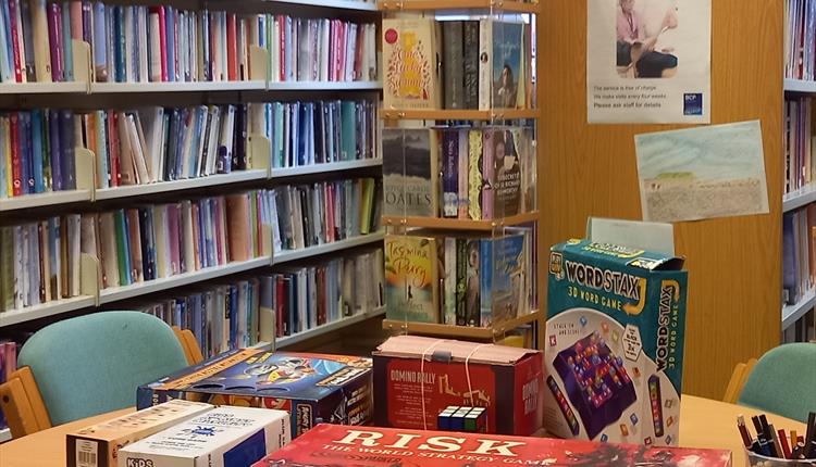 Board games and colouring book on round table, Tuckton Library adult fiction area