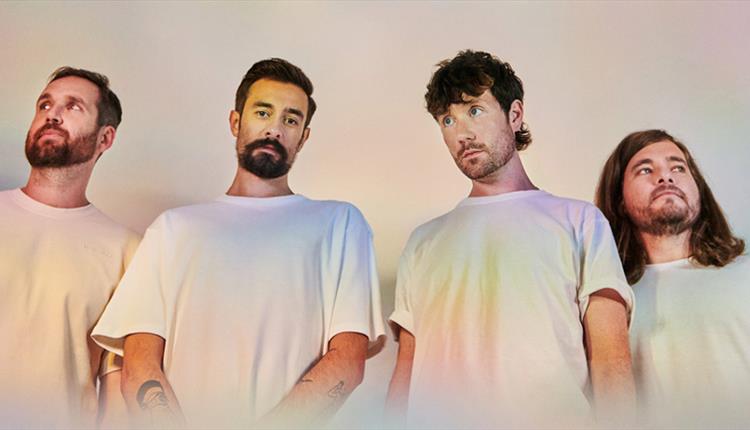 4 men stood in a line wearing white t-shirts.