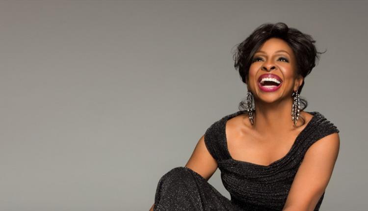 A lady wearing a black dress looking up and smiling.