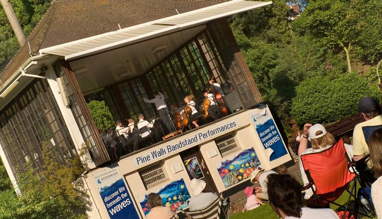 Bandstand event with group of people sitting in the sun enjoying the band