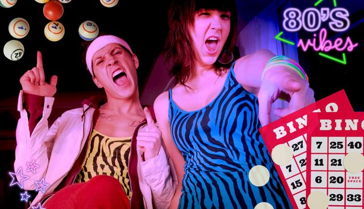 Two people wearing neon outfits surrounded by bingo balls and cards. Boogie Bingo will be 80's themed