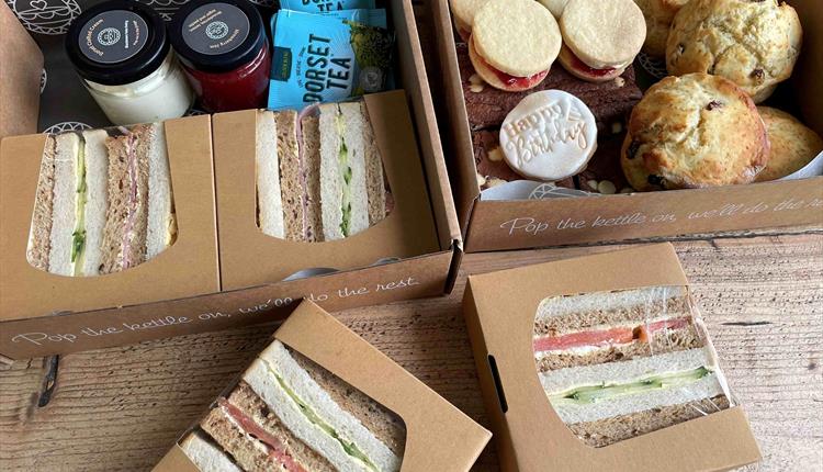 Box filled with afternoon tea, sandwiches and scones