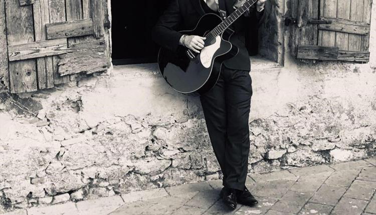 Black and white man in suit playing a guitar