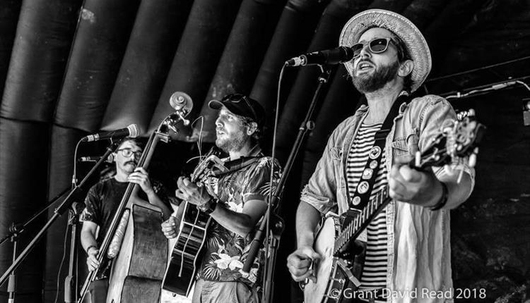 Black & white image of bluegrass band - 3 people playing guitars