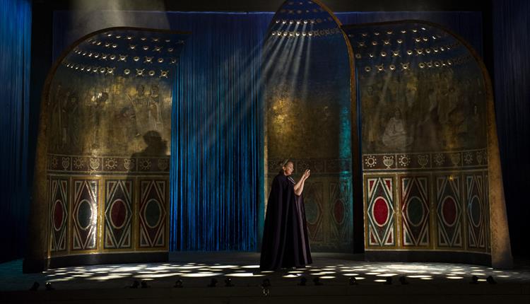 Image of a woman standing in the middle of a stage, looking at her hands