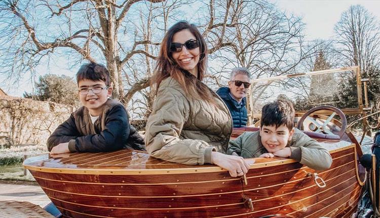 Family sat in an old car smiling at the camera