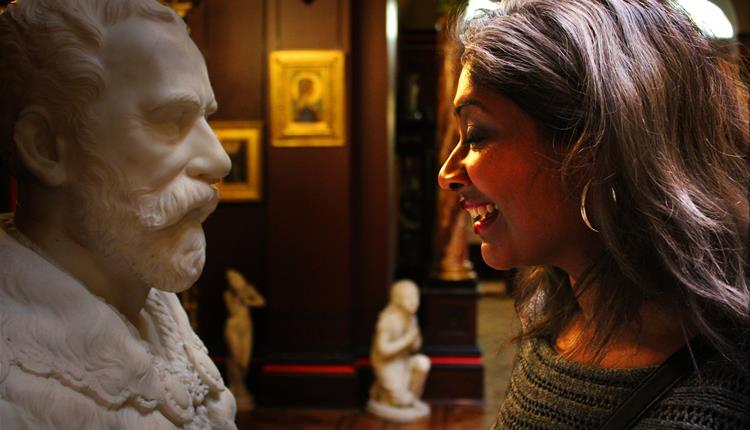 a lady with long hair smiling at a sculpture