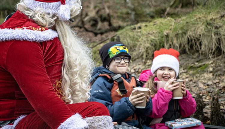 Father Christmas drinking hot chocolate with two children in a kayak