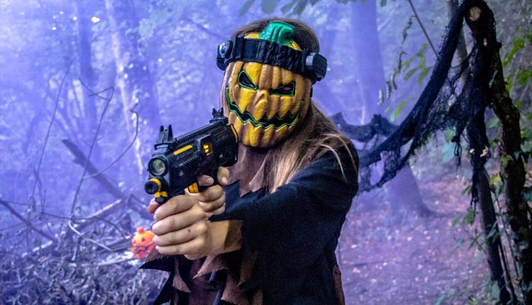 Woman in pumpkin mask holding a laser gun