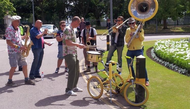 Group of men playing instruments outside on a sunny day