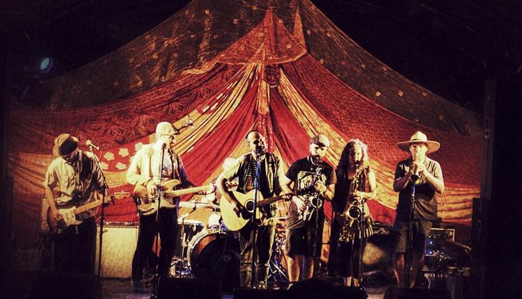 6 piece band playing in a dimly lit marquee