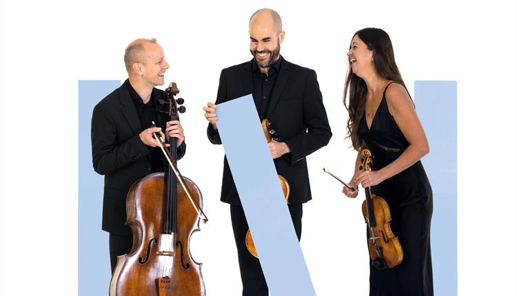 Three musicians are stood amongst blue graphic rectangles, holding their instruments and  laughing.