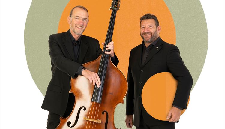 Two musicians are stood, one holding a double bass, in front of coloured graphic circles.