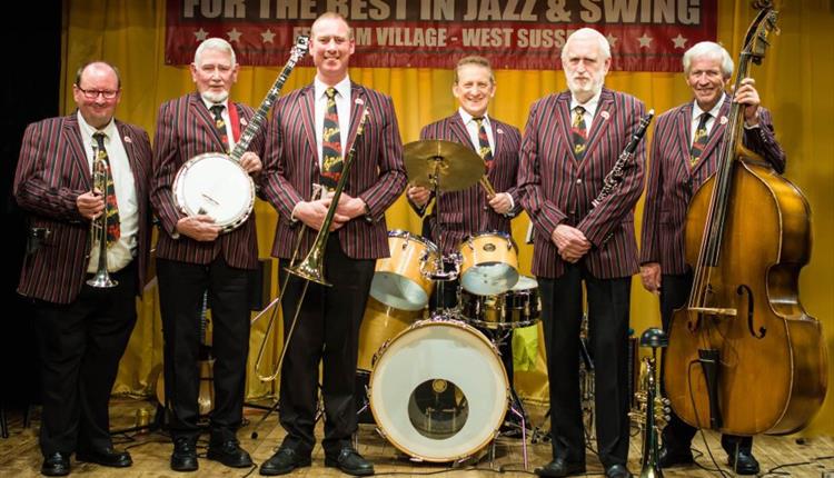 Six piece male traditional jazz band. All facing front, weaing stripy jackets and with the drums centre