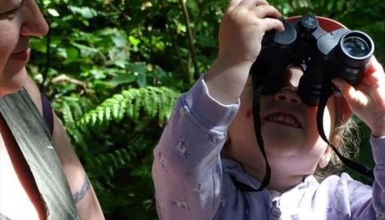 Picture of a woman and child with the child looking through binoculars