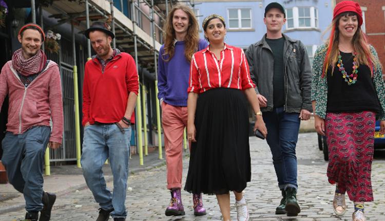 A group of 6 people walking down a cobbled street looking happy and smiling