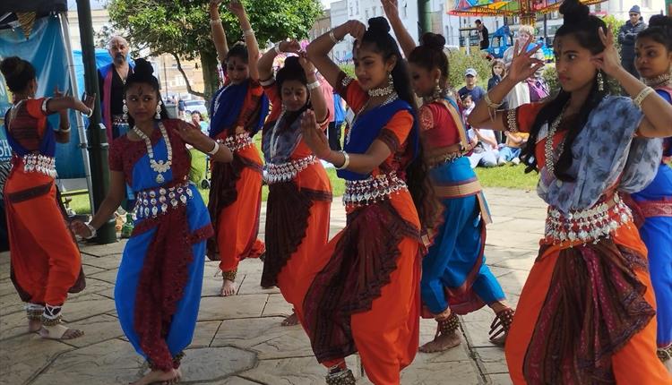 A group of diwali dancers in colourful outfits dancing outside