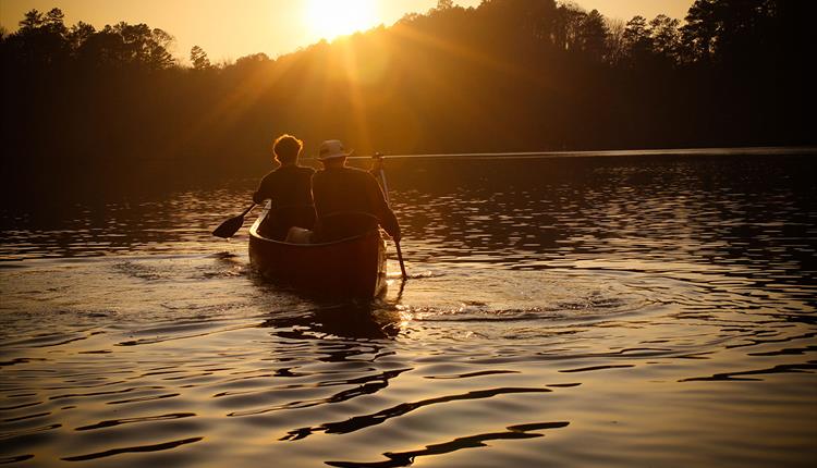 two people in a paddle boat during the sunset
