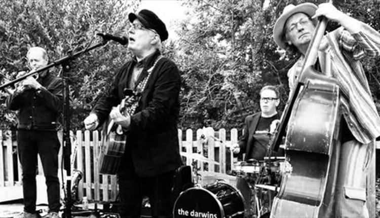 Black and white image of 4 musicians, with double bass in foreground, Vocalist centre and drums and brass in background