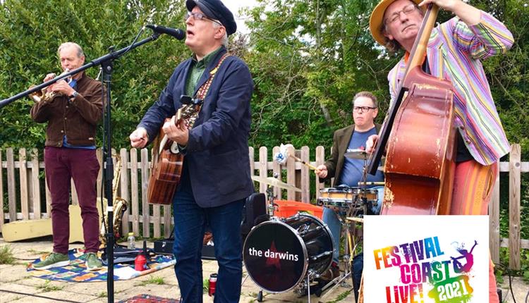 4 piece band with double bass in front of fence & trees