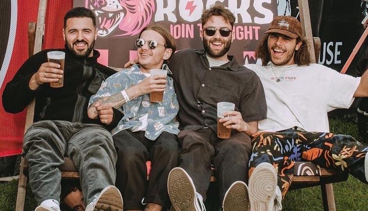 4 people sat on a giant deck chair smiling