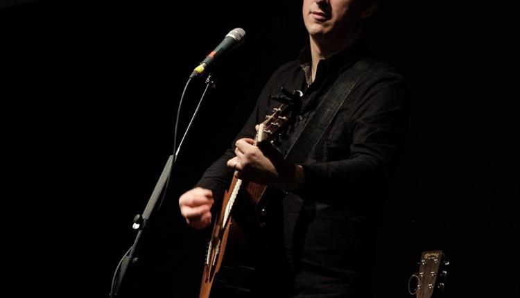 Tom Clements playing his guitar with a microphone