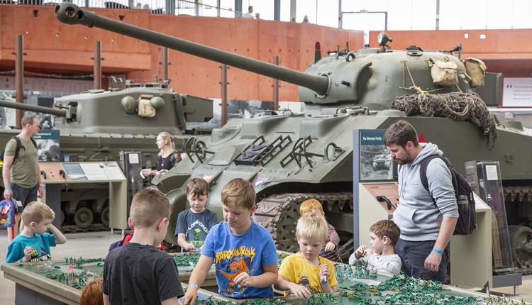 Image of a group of children and one adult in front of a tank