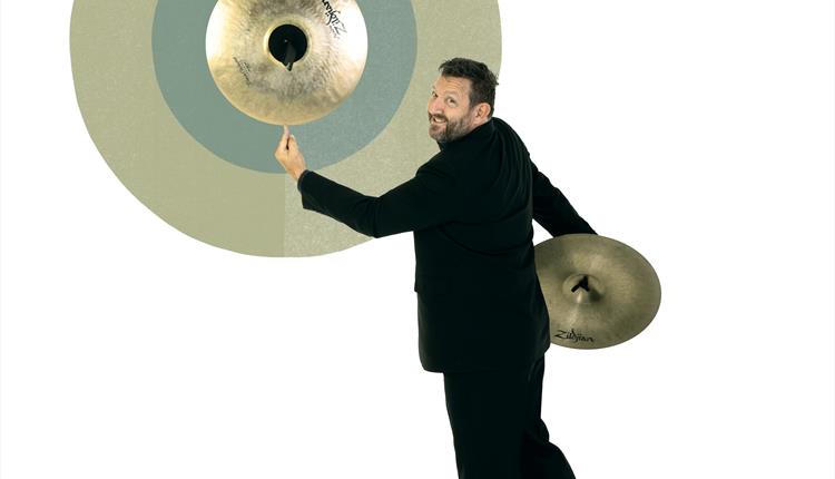 BSO percussionist Matt King is balancing a cymbal on one finger and holding the other cymbal in his other hand.