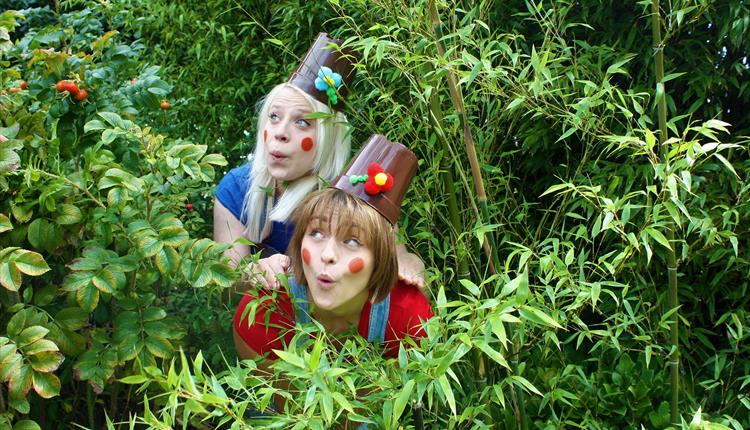 Women pouting in a bush. Dressed up as plants.