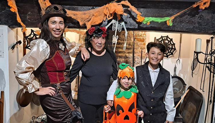 Family of four in Halloween dress stand by spooky fireplace