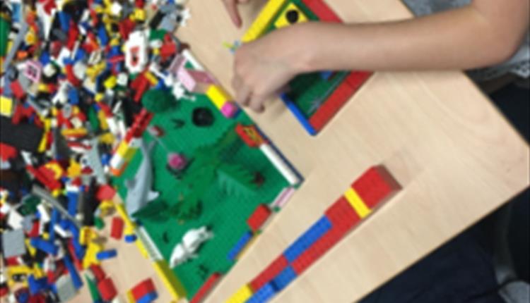 Photo of a child's hands building a Lego world.