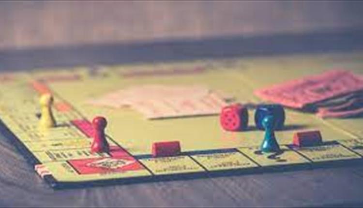 Faded image of a monopoly board showing money, playing pieces and dice