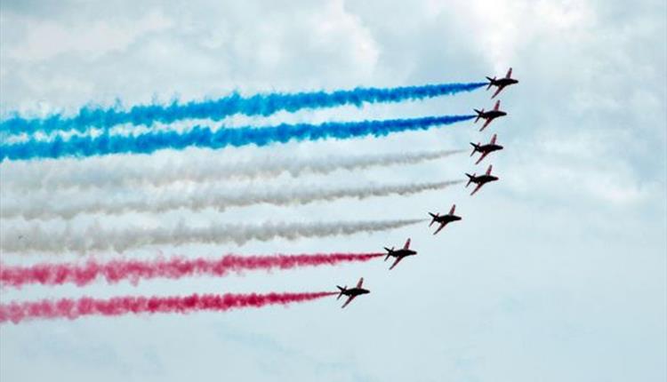 red arrows flying side by side on a cloudy day in the skies