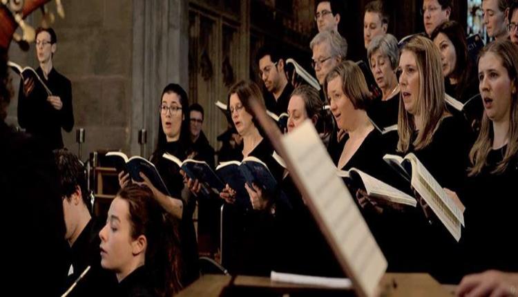 A choir stand singing from open hymn books.