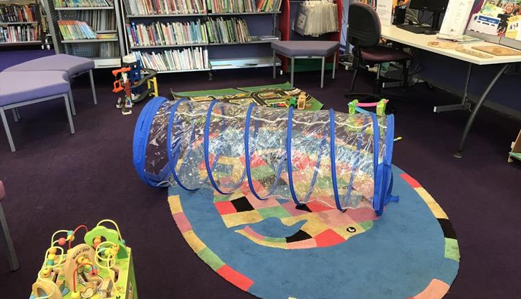 Part of the children's library showing toys including the tunnel, car mat and toy garage.