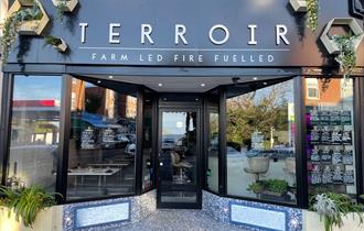 Outside of Terroir with black frontage and plants hanging from the building