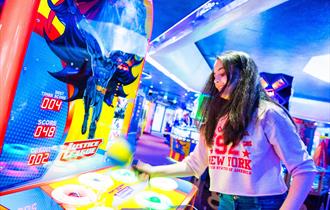 Girl plays a batman themed game in the amusements on Bournemouth Pier
