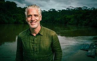 Gordon Buchanan in a green shirt smiling with a lake behind him.