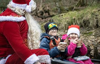 Father Christmas drinking hot chocolate with two children in a kayak